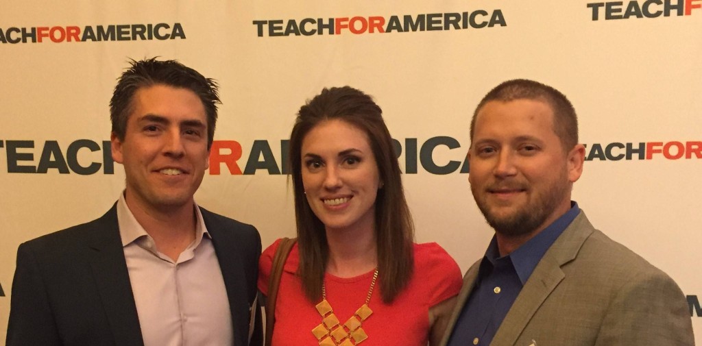Three adults posing before Teach For America backdrop